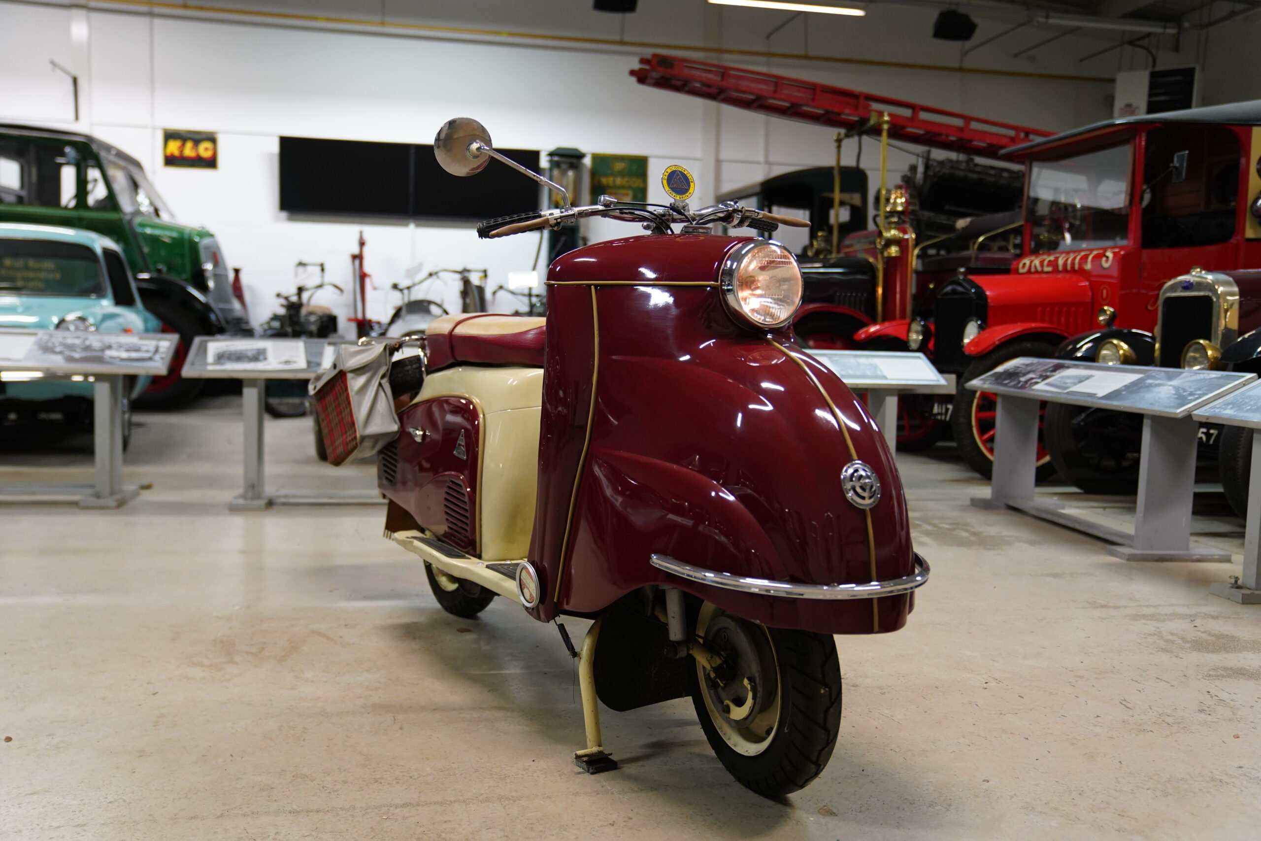 A red and cream 1959 DKR Defiant scooter is parked in the Museum's Bradburn and Wedge Garage.