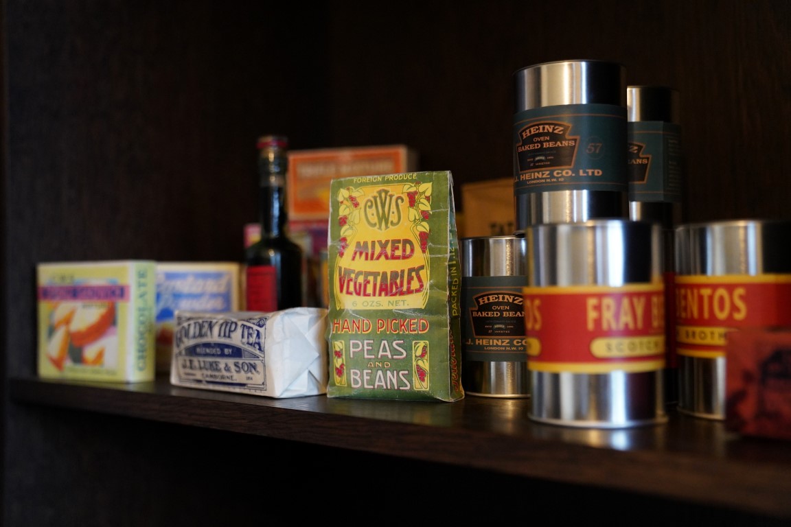 An assortment of historic products, including Heinz Baked Beans, on a wooden shelf.
